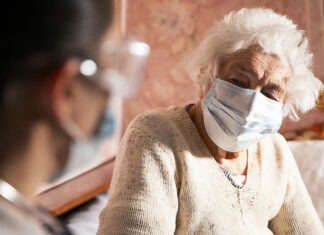 Vaccination rates wane as COVID-19 and influenza cases ramp up vaccinationElderly patient in mask speaking to pharmacist about influenza and COVID-19 vaccination
