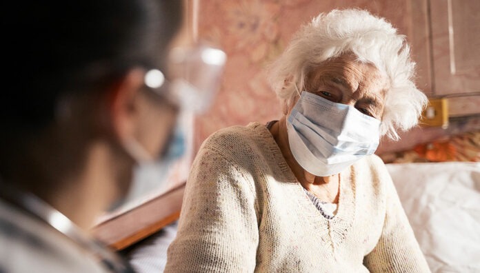 covid-19-aged-care-feature vaccinationElderly patient in mask speaking to pharmacist about influenza and COVID-19 vaccination