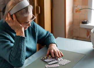 Heading off patient harm from medicines Older woman looking at her medication tablets at a table