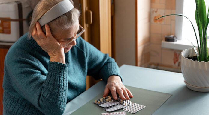 Heading off patient harm from medicines Older woman looking at her medication tablets at a table