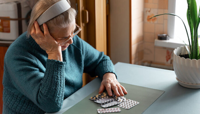 gettyimages-1359233877-170667a Older woman looking at her medication tablets at a table