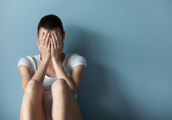 Person exhibiting signs of distress, representing mental health challenges coming out of the shadows in clinical care