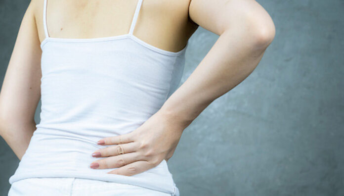 Midsection of female has suffering backache against form work hard A woman holding her lower back in discomfort, illustrating pain associated with kidney stones