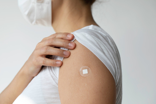 Person showing a bandage on their upper arm after vaccination, highlighting pharmacists practising to full scope by providing immunisation services