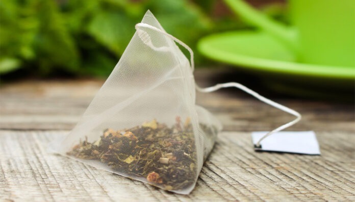 Tea bag on background of mint and and green cup