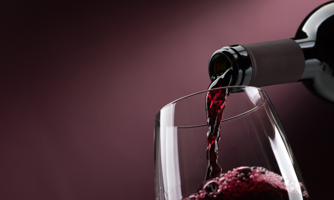 bottle pouring red wine into glass