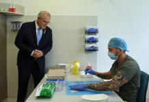 Prime Minister Scott Morrison looks on as pharmacist Branko Radojkovic prepares a simulation of the COVID-19 vaccine at Sydney's Royal Prince Alfred Hospital last week
