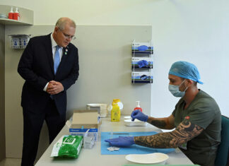 Prime Minister Scott Morrison looks on as pharmacist Branko Radojkovic prepares a simulation of the COVID-19 vaccine at Sydney's Royal Prince Alfred Hospital last week