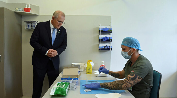 Prime Minister Scott Morrison looks on as pharmacist Branko Radojkovic prepares a simulation of the COVID-19 vaccine at Sydney's Royal Prince Alfred Hospital last week