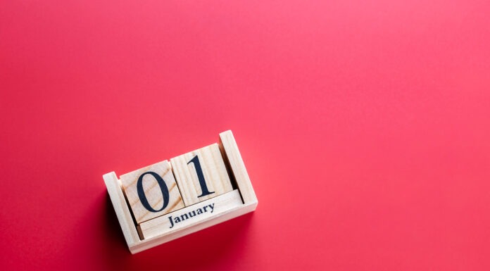 Wooden block calendar with January 01 on red surface, horizontal shot. Clean photo symbolizing New Year and celebration. Concept of new year celebration